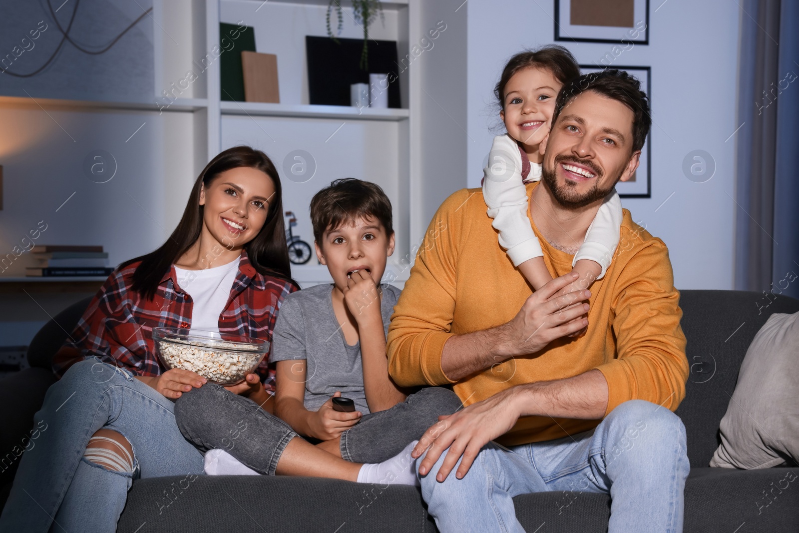 Photo of Happy family watching TV at home in evening