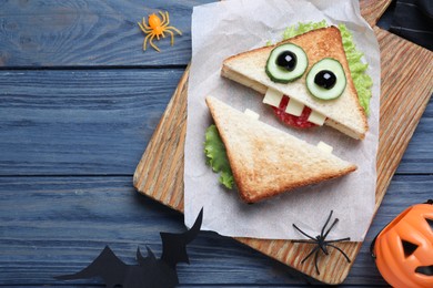 Photo of Cute monster sandwich served on blue wooden table, flat lay. Halloween party food