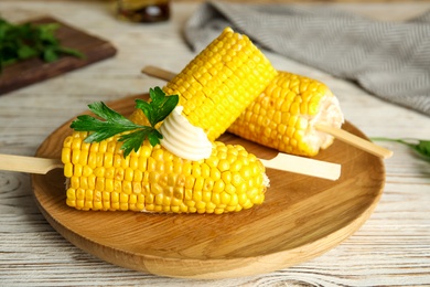 Photo of Fresh corn cobs with butter on wooden table, closeup