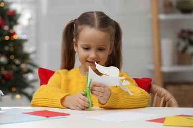 Cute little girl making paper angel for Saint Nicholas day at home