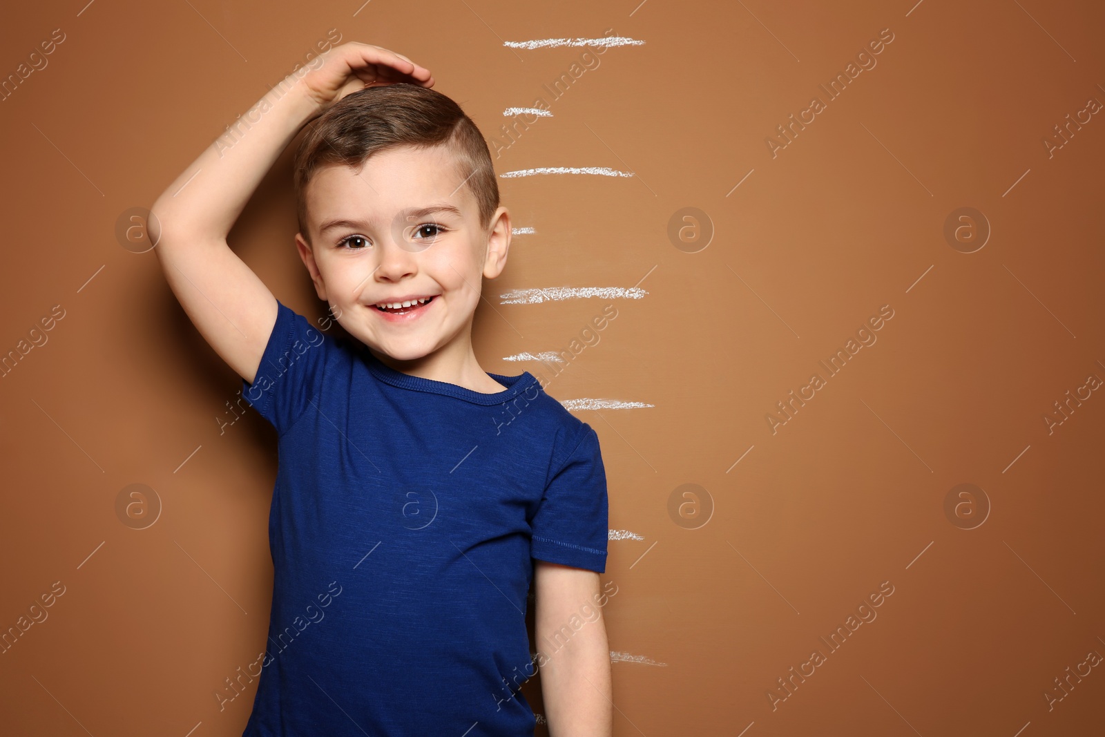 Photo of Little boy measuring his height on color background