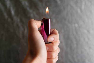 Photo of Woman holding pink lighter on grey background, closeup