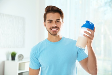 Photo of Young man with bottle of protein shake at home