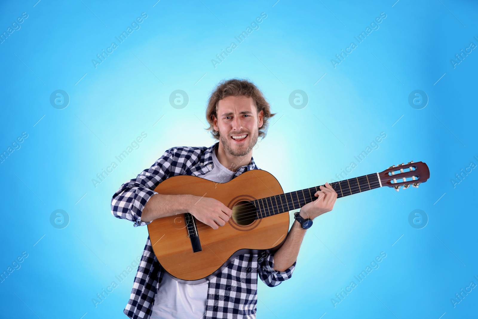 Photo of Young man playing acoustic guitar on color background