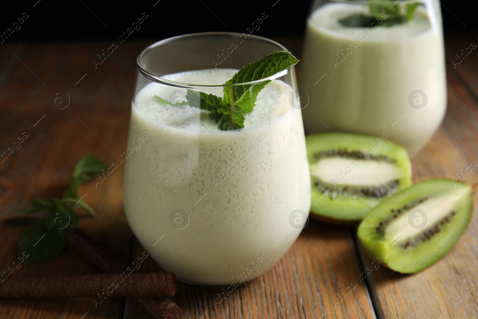 Photo of Tasty milk shake with kiwi on wooden table, closeup