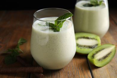 Tasty milk shake with kiwi on wooden table, closeup