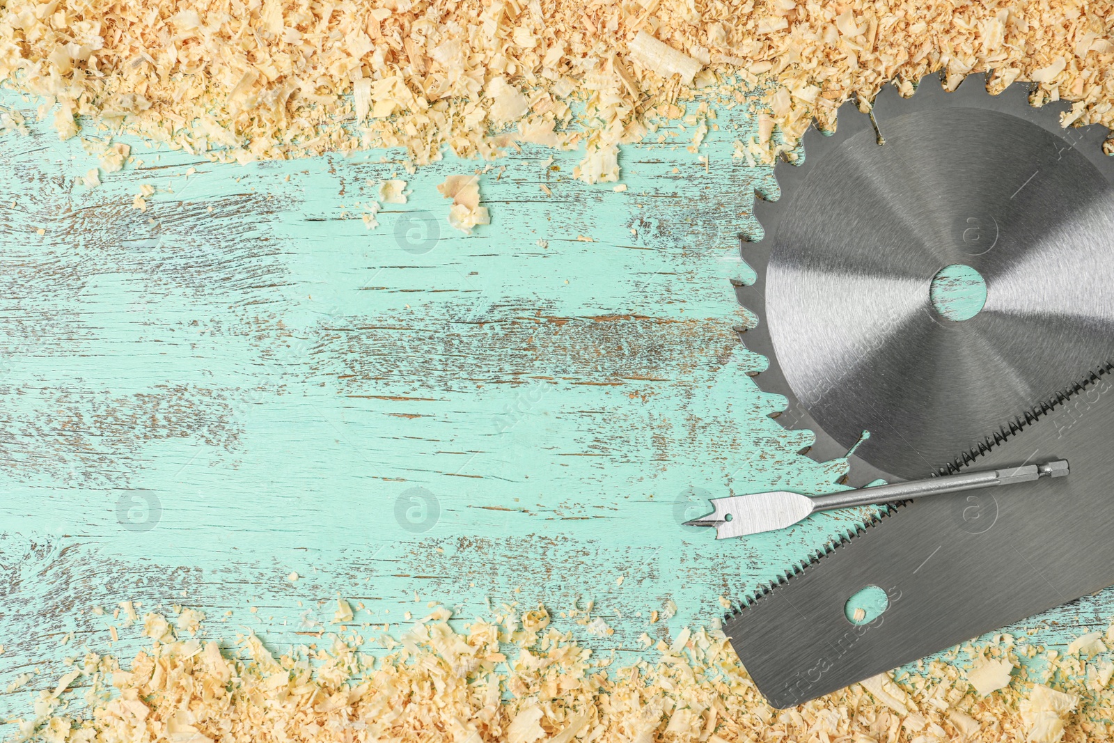 Photo of Modern carpenter's tools and shavings on blue wooden background, flat lay. Space for text