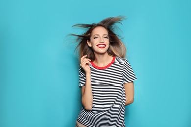 Beautiful young woman with healthy long blonde hair on color background