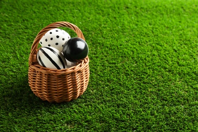 Photo of Wicker basket of painted Easter eggs on green lawn, space for text