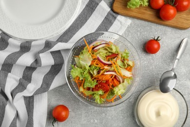 Photo of Delicious salad and bowl of mayonnaise on grey table, flat lay