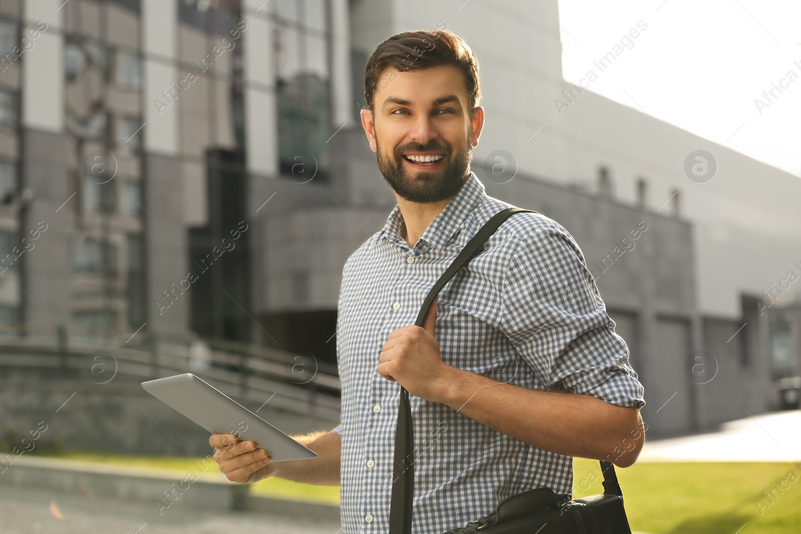 Photo of Handsome man working with tablet on city street