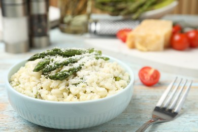 Photo of Delicious risotto with asparagus on wooden table, closeup