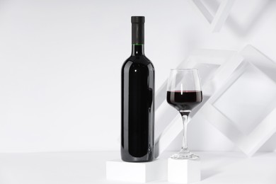 Stylish presentation of delicious red wine in bottle and glass on white background. Space for text