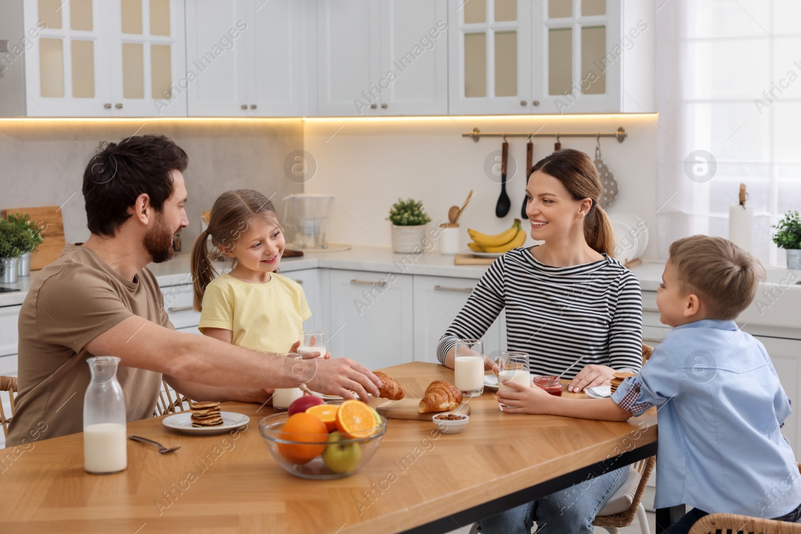 Photo of Happy family having breakfast at table in kitchen