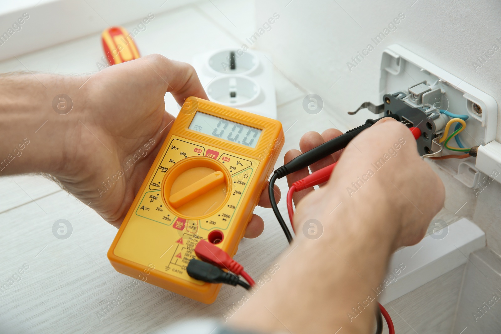 Photo of Electrician with tester checking voltage indoors, closeup