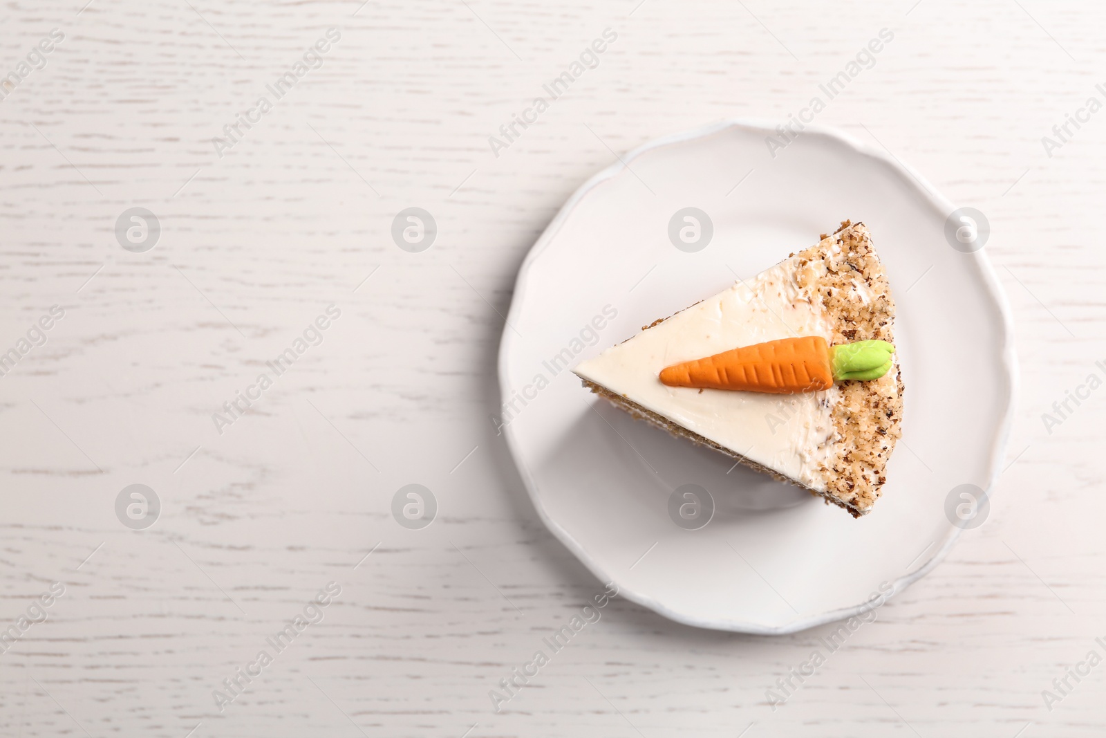 Photo of Piece of sweet carrot cake with delicious cream on white wooden table, top view. Space for text