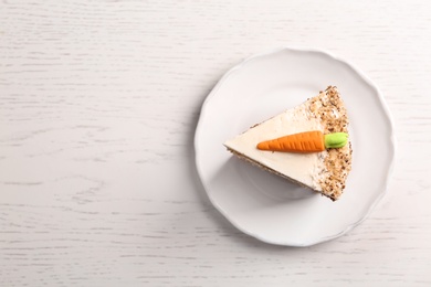 Piece of sweet carrot cake with delicious cream on white wooden table, top view. Space for text