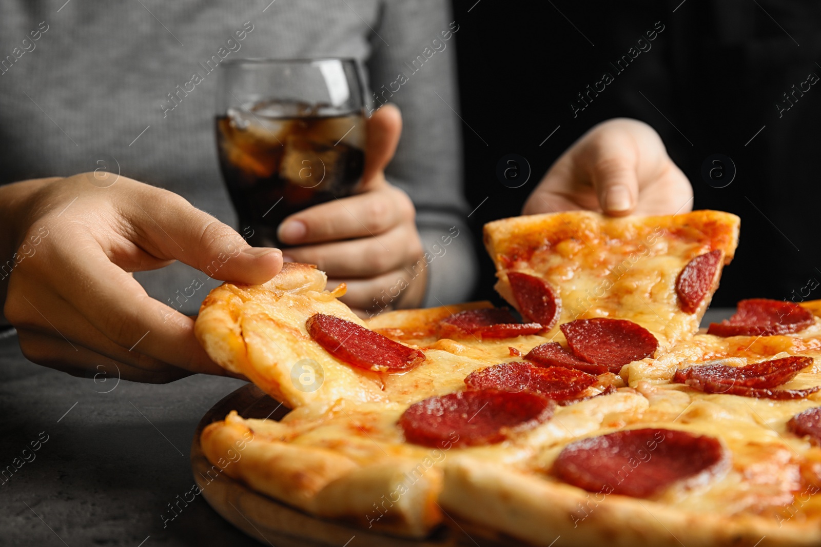 Photo of Women taking tasty pepperoni pizza at grey table, closeup