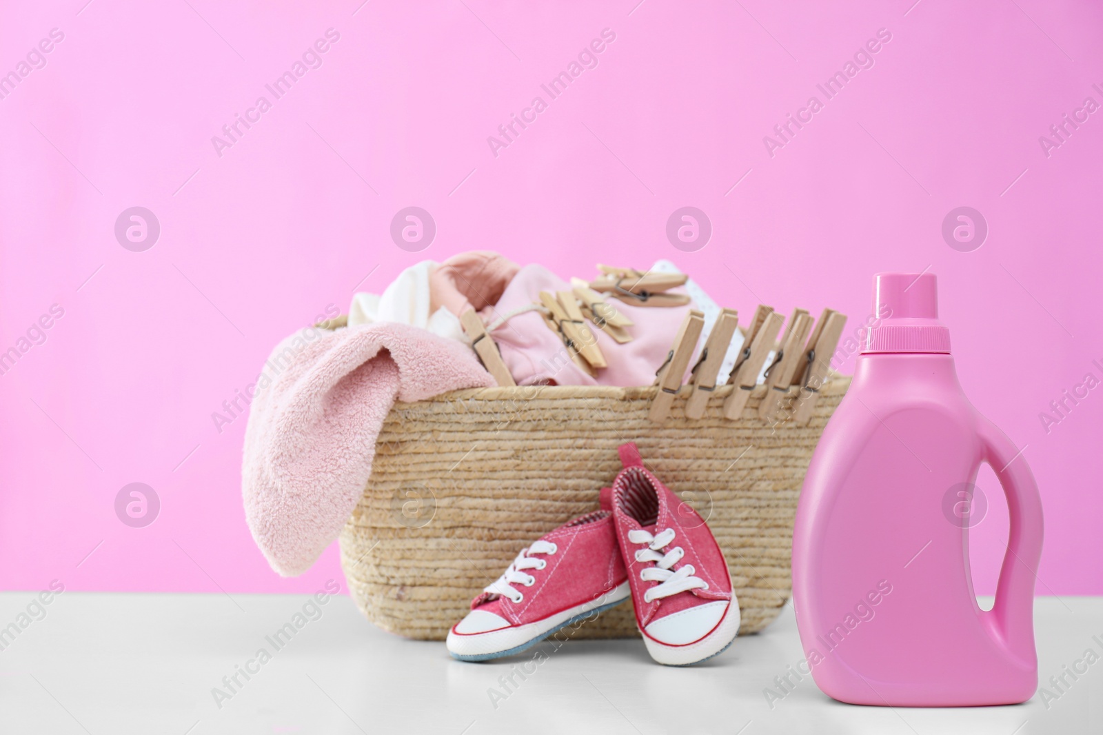 Photo of Detergent and children's clothes on white table