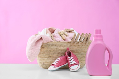 Photo of Detergent and children's clothes on white table