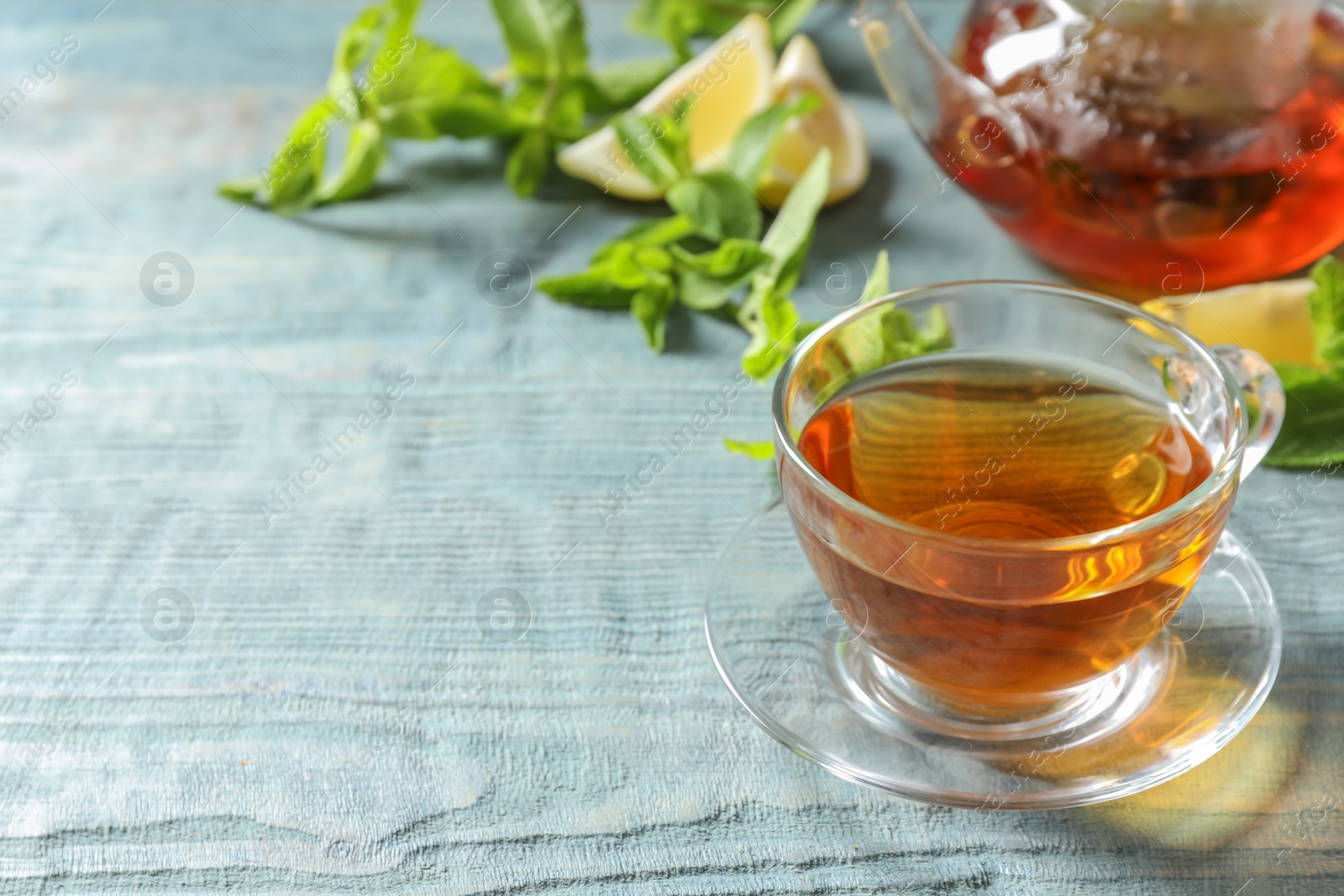 Photo of Cup with hot aromatic mint tea and fresh leaves on table