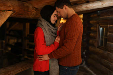 Photo of Lovely couple wearing warm sweaters indoors. Winter season