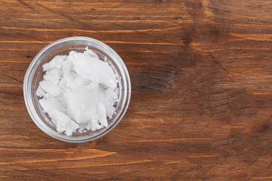 Photo of Organic coconut oil in bowl on wooden table, top view with space for text. Healthy cooking