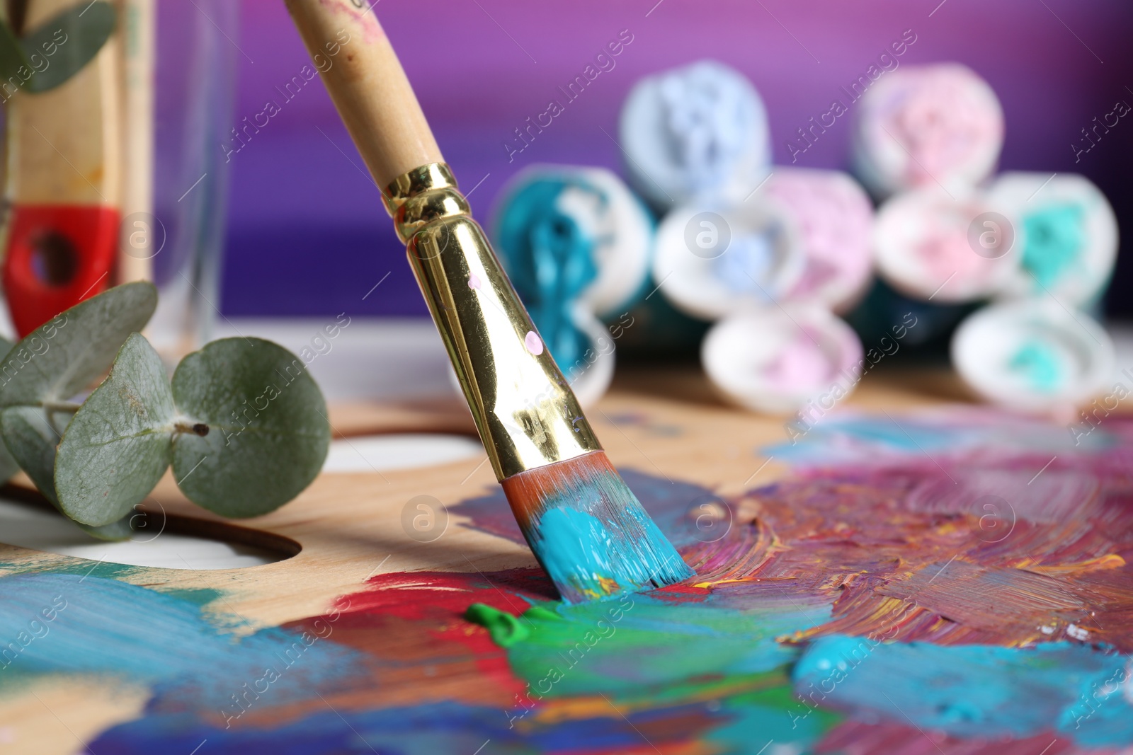 Photo of Mixing colorful paints with brush on wooden artist's palette, closeup