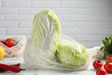 Fresh Chinese cabbages and other vegetables on white marble table near brick wall