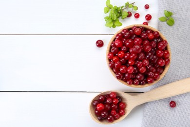 Photo of Fresh ripe cranberries and branches on white wooden table, top view. Space for text