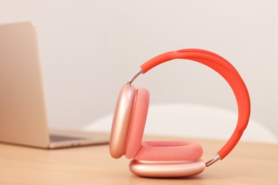 Photo of Modern headphones and laptop on wooden table