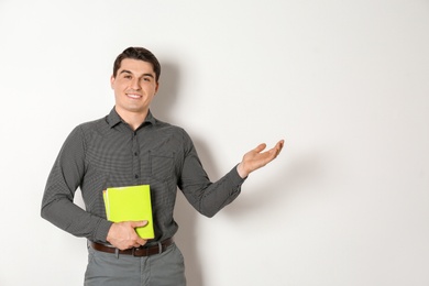 Photo of Portrait of male teacher with notebooks on light background