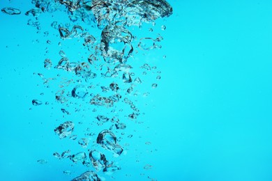 Image of Many air bubbles in water on light blue background, space for text