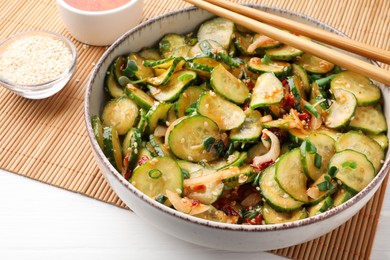 Photo of Bowl of delicious cucumber salad served on white wooden table, closeup