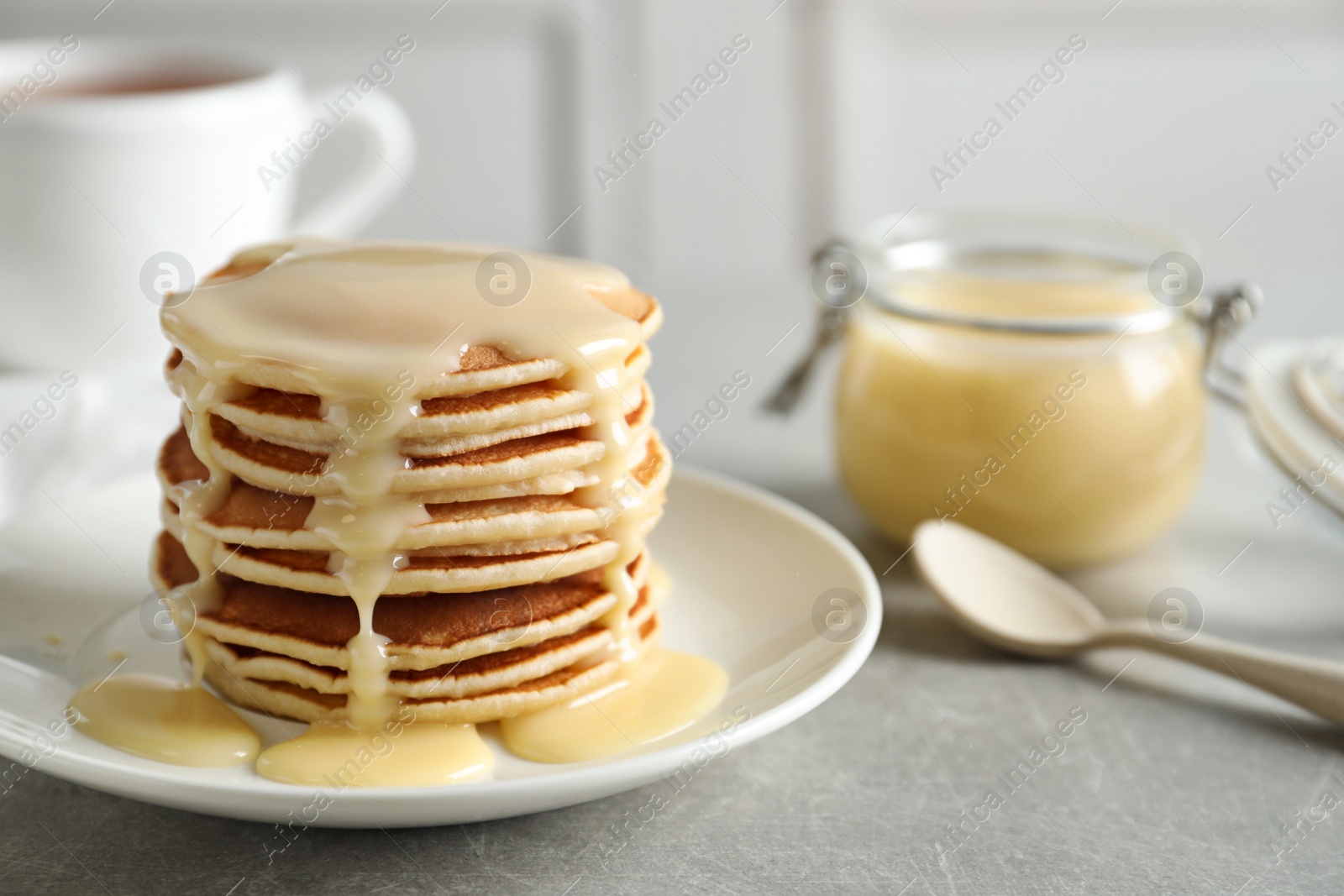 Photo of Plate with pancakes and condensed milk served on table, space for text. Dairy product