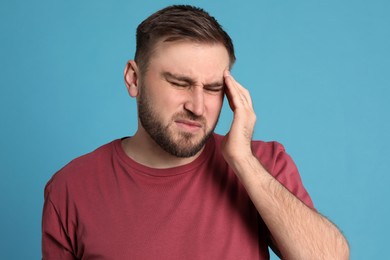 Photo of Man suffering from migraine on light blue background