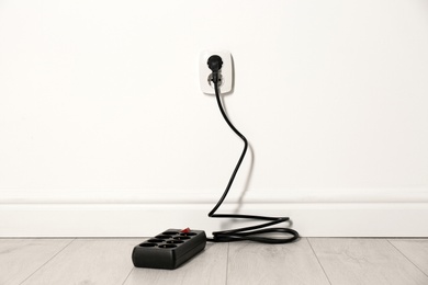 Photo of Extension cord with power plug in socket indoors. Electrician's professional equipment