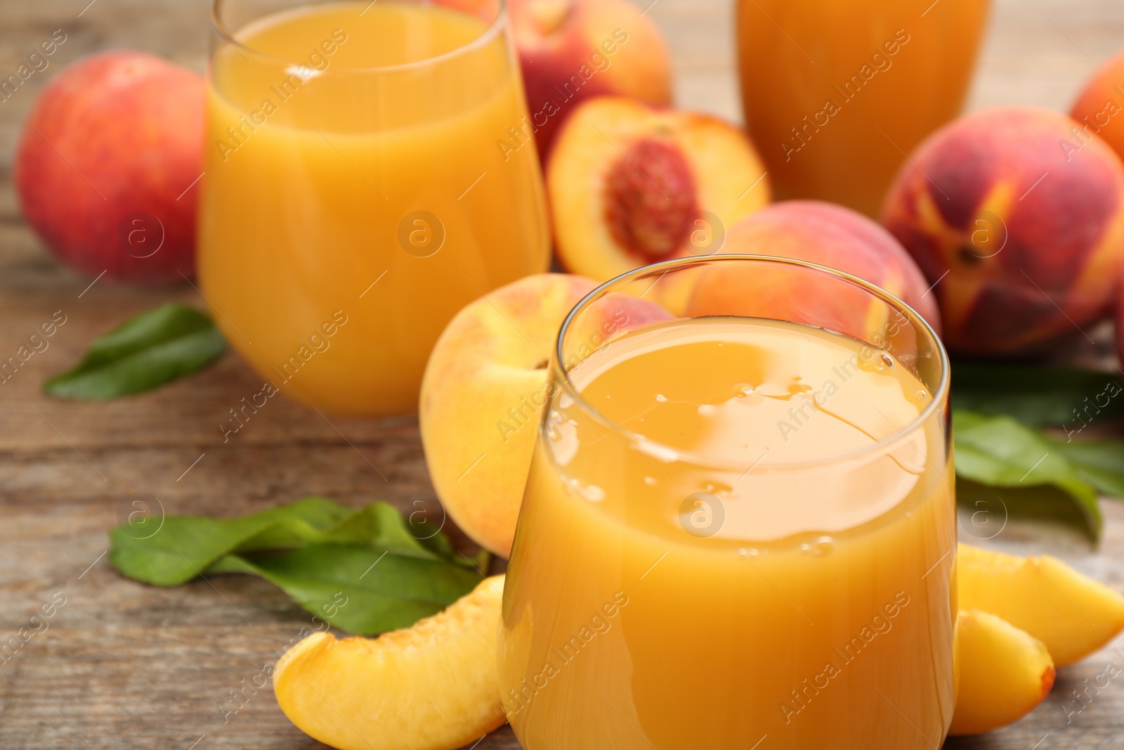 Photo of Natural peach juice and fresh fruits on wooden table, closeup