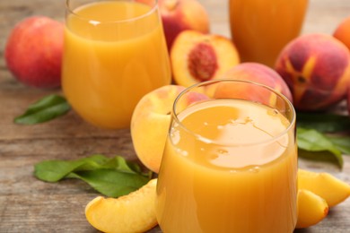 Photo of Natural peach juice and fresh fruits on wooden table, closeup