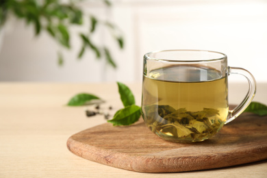 Tasty hot green tea in cup on wooden table, closeup