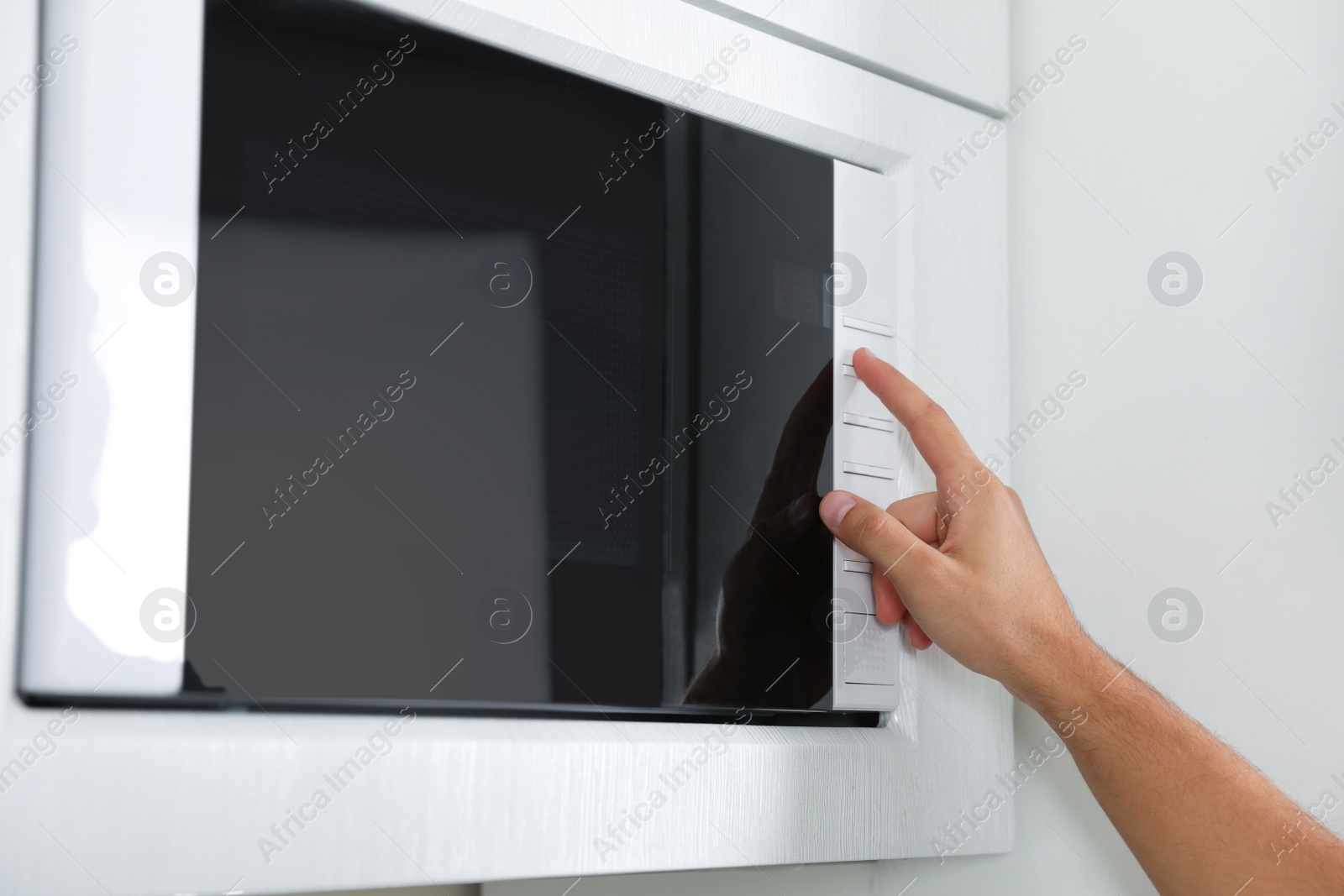 Photo of Young man using modern microwave oven, closeup