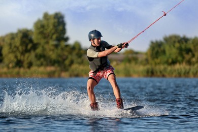 Teenage boy wakeboarding on river. Extreme water sport