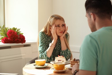 Photo of Young woman getting bored during first date with man in cafe