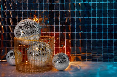 Photo of Many shiny disco balls on floor near foil party curtain. Space for text