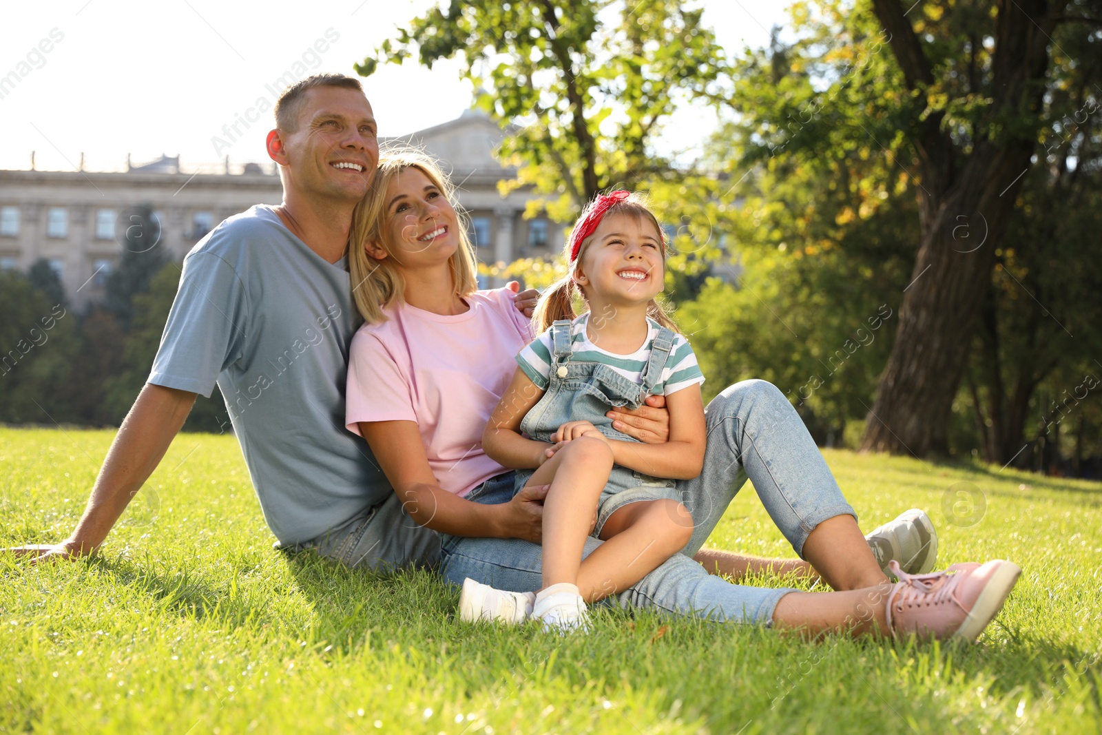 Photo of Happy parents with their child having fun on green grass. Spending time in nature