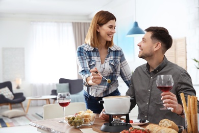 Happy couple enjoying fondue dinner at home