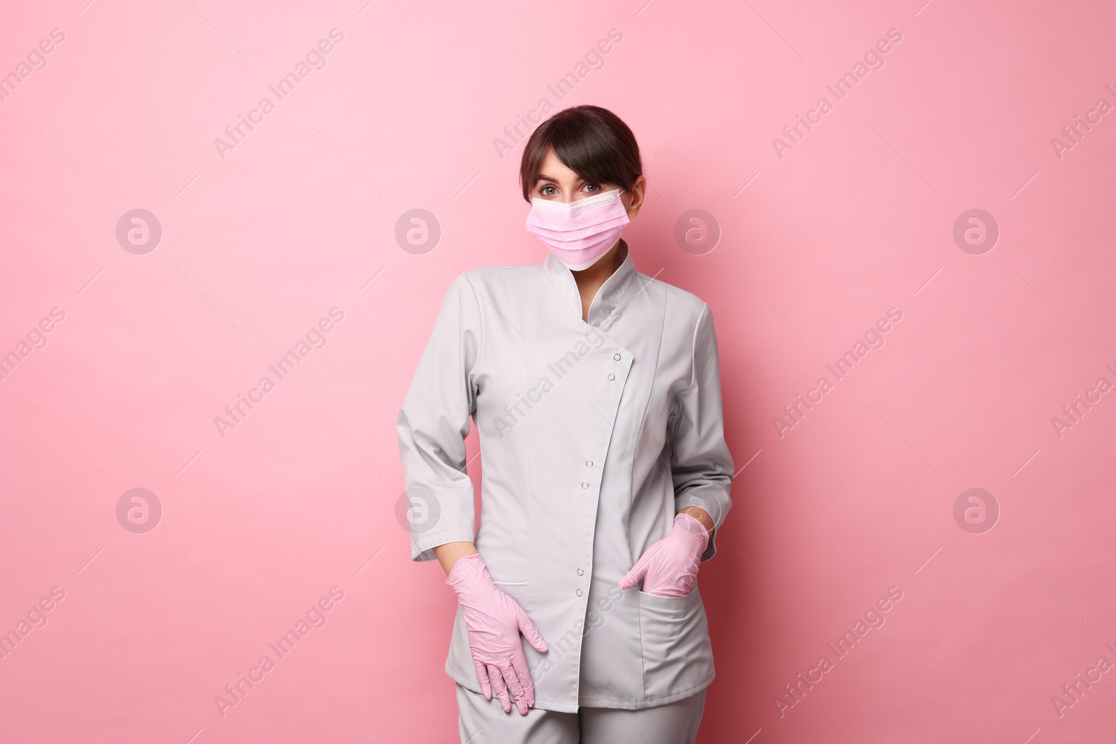 Photo of Cosmetologist in medical uniform on pink background