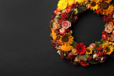 Beautiful autumnal wreath with flowers, berries and fruits on black background, top view. Space for text