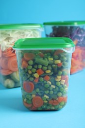 Set of plastic containers with fresh food on light blue background