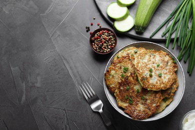 Photo of Delicious zucchini fritters served on grey table, flat lay. Space for text